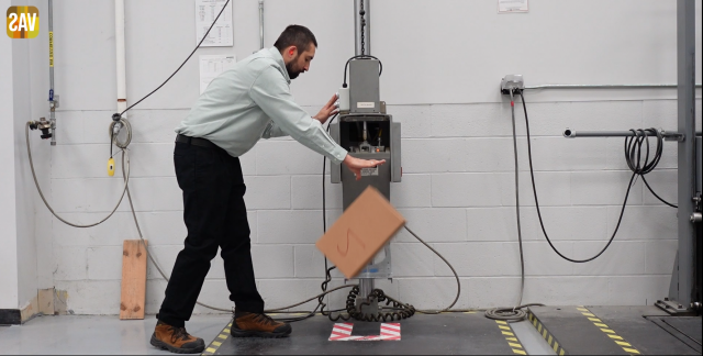 an employee at the Value-Added Services lab performs a drop test on a corrugated box